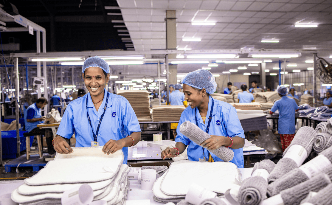 Two workers smiling in an assembly and packaging facility.