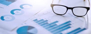 Glasses sitting on top of papers with charts and graphs